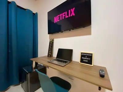 a desk with a laptop and a television on a wall at Prosperity Room, Habitación doble - solo a una cuadra del parque in Carmen de Viboral
