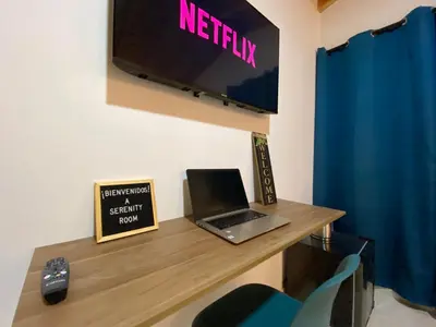a laptop on a desk with a tv on a wall at Serenity Room, Habitación doble - solo a una cuadra del parque in Carmen de Viboral