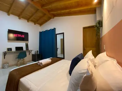 a bedroom with a bed with a tv on the wall at Serenity Room, Habitación doble - solo a una cuadra del parque in Carmen de Viboral