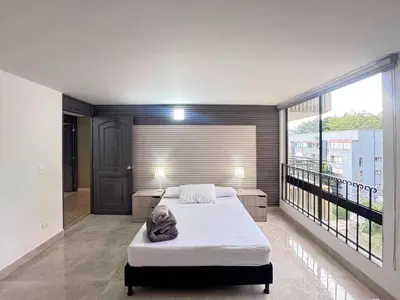 a bedroom with a bed and a large window at 5BR 232 m² apartment in El Poblado, El Tesoro in Medellín