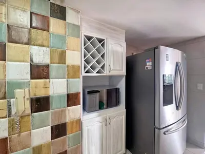 a kitchen with a refrigerator and a tile wall at 5BR 232 m² apartment in El Poblado, El Tesoro in Medellín