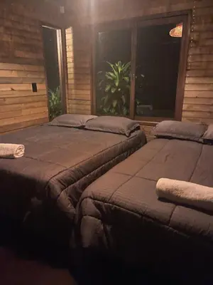two beds sitting in a room with a window at Rancho Forest Guatape in Guatapé