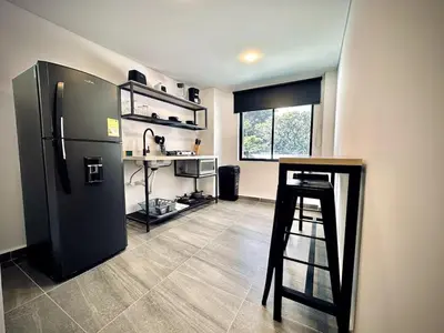 a kitchen with a black refrigerator and a stool at Loft 203 Laureles Le meilleur emplacement WIFI Toit in Medellín