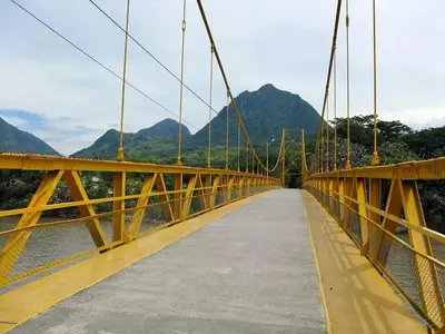 a bridge over a river with mountains in the background at Habitación sencilla con desayuno - La Casona Hotel in La Pintada