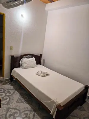 a small bed in a room with a white bedspread at Habitación sencilla con desayuno - La Casona Hotel in La Pintada