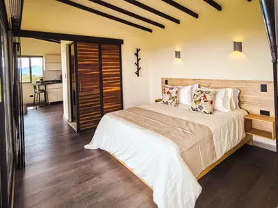 a bedroom with a large bed and a kitchen at Alto Sereno in Horizonte