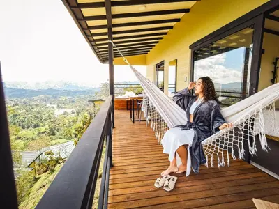 a couple sitting on a hammock on the balcony of a house at Alto Sereno in Horizonte