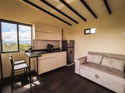 a living room with a couch and a kitchen at Alto Sereno in Horizonte