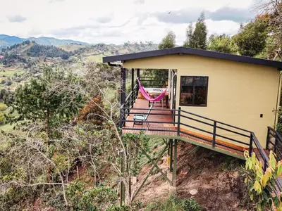 a house on the side of a hill with a hammock at Alto Sereno in Horizonte