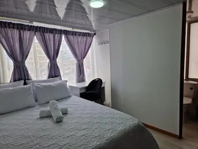 a bedroom with a large bed with purple curtains at Habitación baño privado garaje moto, Manizales in Manizales