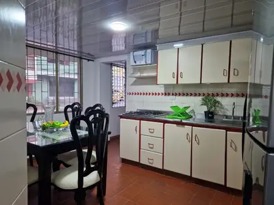a kitchen with white cabinets and a table and a table and chairs at Habitación baño privado garaje moto, Manizales in Manizales