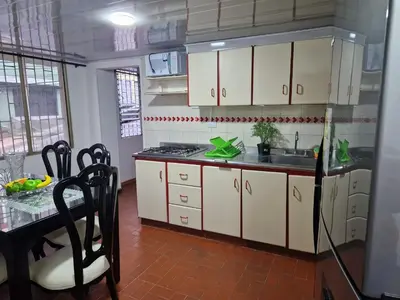 a kitchen with white cabinets and a sink and a table at Habitación baño privado garaje moto, Manizales in Manizales