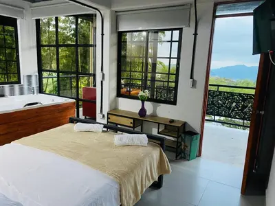 a bedroom with a bed and a tub and windows at Curazao Natural Living in Cocorná
