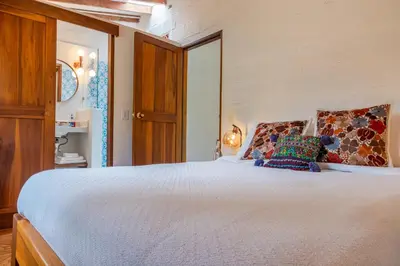 a bedroom with a large white bed with colorful pillows at Organic Finca with Modern Amenities in Jericó