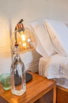 a glass bottle on a table next to a bed at Organic Finca with Modern Amenities in Jericó