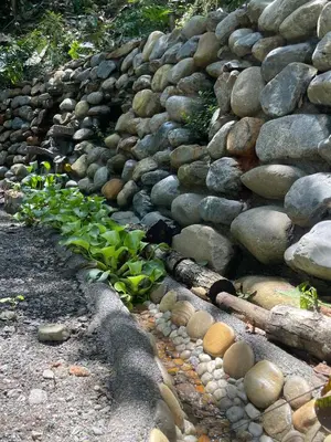 a stone wall with a bunch of rocks and plants at Cascadia in Cocorná