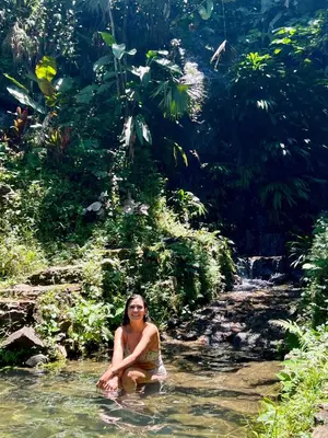 a woman sitting in the water in a river at Cascadia in Cocorná