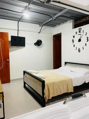 a room with two beds and a clock on the wall at Hotel Curazao Natural Living in Cocorná
