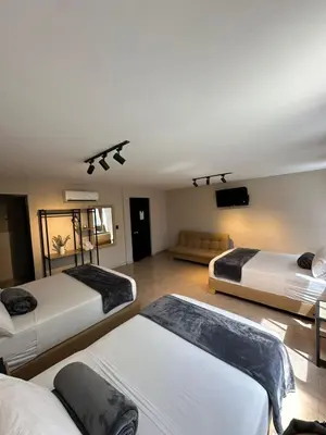 a room with three beds and a flat screen tv at Hotel Coral Boutique in Medellín