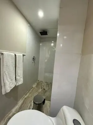 a white bathroom with a toilet and a shower at Hotel Coral Boutique in Medellín