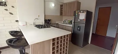 a kitchen with a refrigerator and a counter with stools at ApartaLoft, Belén, Medellín in Medellín
