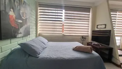 a bedroom with a bed and a window with a television at ApartaLoft, Belén, Medellín in Medellín