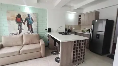a living room with a couch and a kitchen at ApartaLoft, Belén, Medellín in Medellín