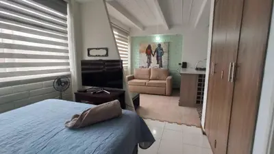 a bedroom with a bed and a couch and a television at ApartaLoft, Belén, Medellín in Medellín