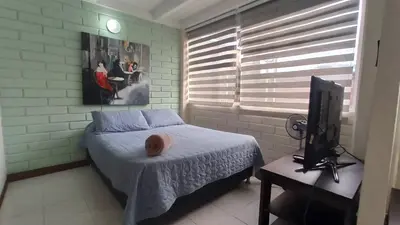 a bedroom with a bed and a tv and a window at ApartaLoft, Belén, Medellín in Medellín