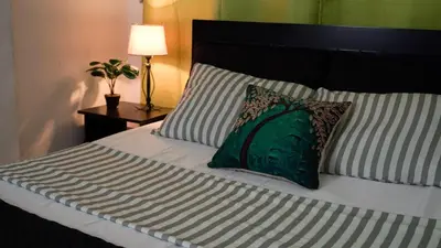 a bedroom with a bed with a green pillow and a lamp at Casa MoraZ in Medellín