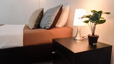 a bedroom with a bed with pillows and a table with a lamp at Casa MoraZ in Medellín