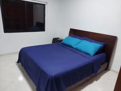 a bedroom with a bed with blue pillows and a window at San Antonio in El Peñol