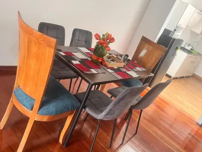a dining room table with chairs and a table with flowers on it at Urbanhost in Manizales