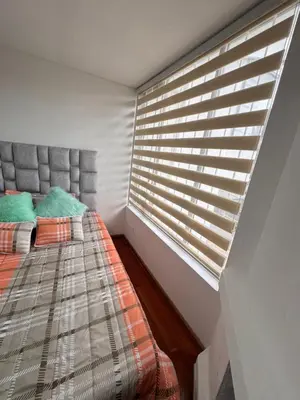 a bedroom with a bed and a window with blinds at Urbanhost in Manizales