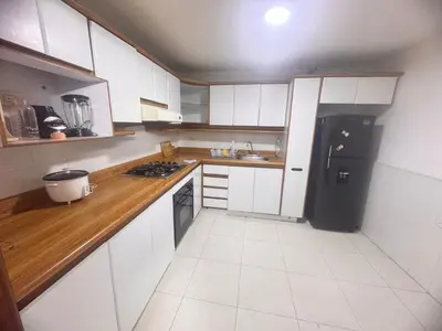 a kitchen with white cabinets and a black refrigerator at Urbanhost in Manizales