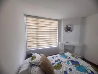 a bedroom with a bed and a window with blinds at Urbanhost in Manizales