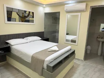 a bedroom with a bed and a sink and a mirror at Hotel Magistral Suiter in Quibdó