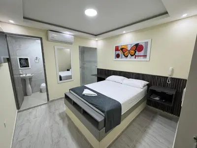 a bedroom with a bed and a bathroom with a shower at Hotel Magistral Suiter in Quibdó