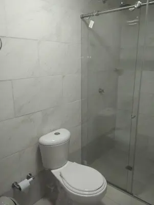 a bathroom with a toilet and a glass shower at Hotel Magistral Suiter in Quibdó