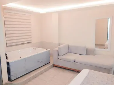 a white bathroom with a tub and a couch at Hotel Magistral Suiter in Quibdó