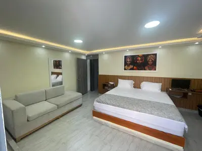 a bedroom with a large bed and a couch at Hotel Magistral Suiter in Quibdó