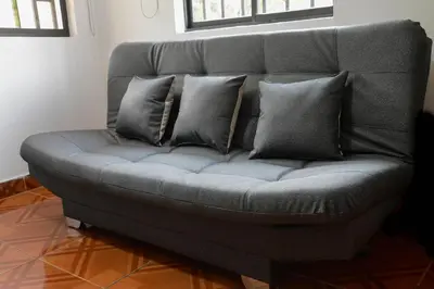 a grey couch with four pillows on it at Apto Acogedor Cerca Metrocable in Medellín