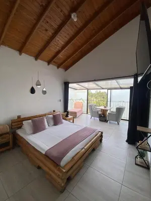 a bedroom with a large bed and a living room at Hotel Volcán Campestre Guatapé in Guatapé