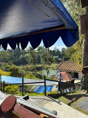 a blue umbrella over a table with a view of a river at Hotel Volcán Campestre Guatapé in Guatapé