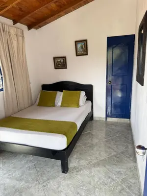 a bedroom with a bed and a blue door at Hotel Volcán Campestre Guatapé in Guatapé