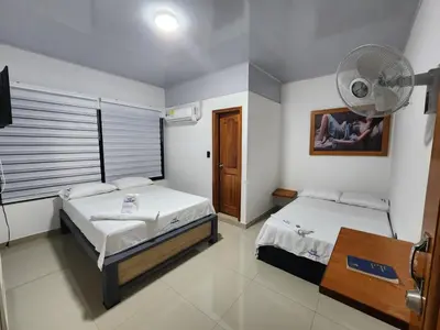 a bedroom with two beds and a fan at Hotel tranquilandia La 14 in La Dorada