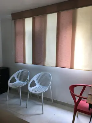 two white chairs sitting in a room with windows at Apartamentos Amoblados JG de la 70 in Medellín