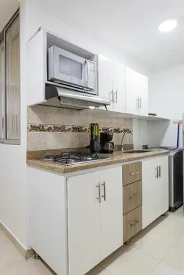 a kitchen with white cabinets and a microwave at Apartamentos Amoblados JG de la 70 in Medellín