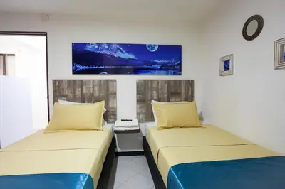 two beds in a room with a tv on the wall at Apartamentos Amoblados JG de la 70 in Medellín