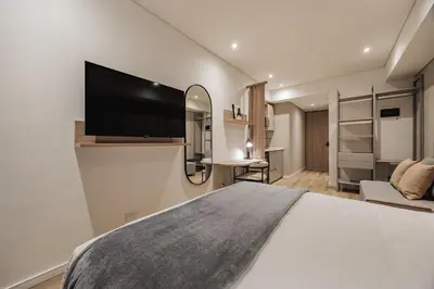 a bedroom with a large bed and a flat screen tv at Quadrato Studios in Medellín